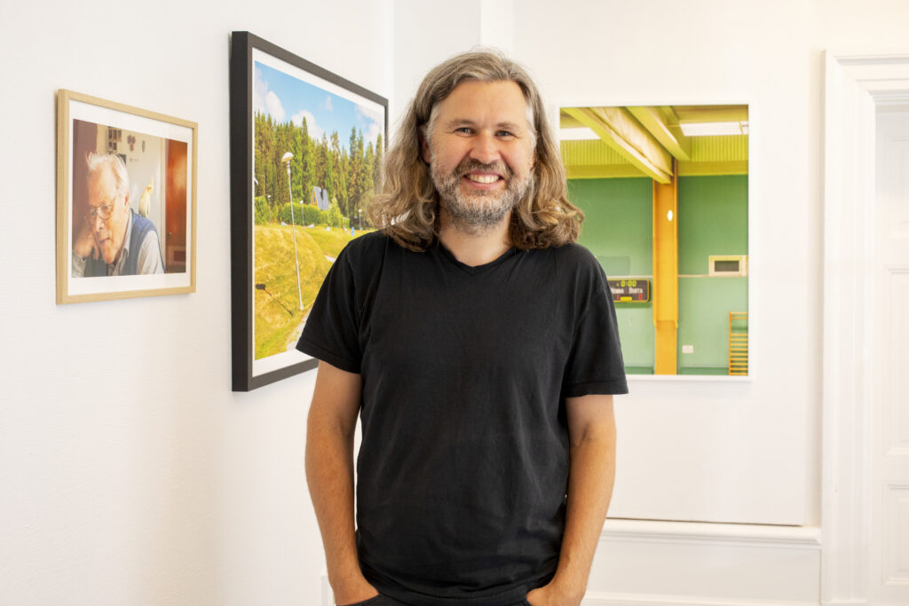 Fotografen Gustav Gräll framför verk i utställningen Sverige på Härnösands Konsthall